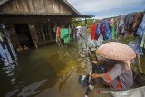 Warga menggunakan perahu untuk mencuci pakaian di depan rumahnya yang terendam banjir di Desa Sungai Batang, Kabupaten Banjar, Kalimantan Selatan, Rabu (6/1/2021). Menurut Badan Penanggulangan Bencana Daerah (BPBD) Kabupaten Banjar, banjir setinggi lima hingga satu meter yang melanda pemukiman di sejumlah desa di Kabupaten Banjar tersebut dipicu oleh hujan dengan intensitas tinggi sehingga menyebabkan debit air sungai Martapura meluap. Foto Antaranews Kalsel/Bayu Pratama S.