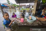 Sejumlah warga beraktivitas di depan rumah yang terendam banjir di Desa Sungai Rangas Ulu, Kabupaten Banjar, Kalimantan Selatan, Rabu (6/1/2021). Menurut Badan Penanggulangan Bencana Daerah (BPBD) Kabupaten Banjar, banjir setinggi lima hingga satu meter yang melanda pemukiman di sejumlah desa di Kabupaten Banjar tersebut dipicu oleh hujan dengan intensitas tinggi sehingga menyebabkan debit air sungai Martapura meluap.Foto Antaranews Kalsel/Bayu Pratama S.