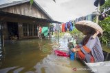 Warga menggunakan perahu untuk mencuci pakaian di depan rumahnya yang terendam banjir di Desa Sungai Batang, Kabupaten Banjar, Kalimantan Selatan, Rabu (6/1/2021). Menurut Badan Penanggulangan Bencana Daerah (BPBD) Kabupaten Banjar, banjir setinggi lima hingga satu meter yang melanda pemukiman di sejumlah desa di Kabupaten Banjar tersebut dipicu oleh hujan dengan intensitas tinggi sehingga menyebabkan debit air sungai Martapura meluap. Foto Antaranews Kalsel/Bayu Pratama S.