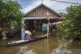 Warga beraktivitas di depan rumahnya yang terendam banjir di Desa Sungai Batang, Kabupaten Banjar, Kalimantan Selatan, Rabu (6/1/2021). Menurut Badan Penanggulangan Bencana Daerah (BPBD) Kabupaten Banjar, banjir setinggi lima hingga satu meter yang melanda pemukiman di sejumlah desa di Kabupaten Banjar tersebut dipicu oleh hujan dengan intensitas tinggi sehingga menyebabkan debit air sungai Martapura meluap. Foto Antaranews Kalsel/Bayu Pratama S.