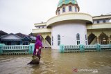 Warga melintasi banjir di Desa Dalam Pagar Ulu, Kabupaten Banjar, Kalimantan Selatan, Rabu (6/1/2021). Menurut Badan Penanggulangan Bencana Daerah (BPBD) Kabupaten Banjar, banjir setinggi lima hingga satu meter yang melanda pemukiman di sejumlah desa di Kabupaten Banjar tersebut dipicu oleh hujan dengan intensitas tinggi sehingga menyebabkan debit air sungai Martapura meluap. Foto Antaranews Kalsel/Bayu Pratama S.