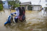 Warga melintasi banjir di Desa Dalam Pagar Ulu, Kabupaten Banjar, Kalimantan Selatan, Rabu (6/1/2021). Menurut Badan Penanggulangan Bencana Daerah (BPBD) Kabupaten Banjar, banjir setinggi lima hingga satu meter yang melanda pemukiman di sejumlah desa di Kabupaten Banjar tersebut dipicu oleh hujan dengan intensitas tinggi sehingga menyebabkan debit air sungai Martapura meluap. Foto Antaranews Kalsel/Bayu Pratama S.