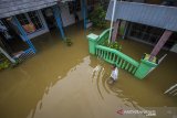 Warga melintasi banjir di Desa Dalam Pagar Ulu, Kabupaten Banjar, Kalimantan Selatan, Rabu (6/1/2021). Menurut Badan Penanggulangan Bencana Daerah (BPBD) Kabupaten Banjar, banjir setinggi lima hingga satu meter yang melanda pemukiman di sejumlah desa di Kabupaten Banjar tersebut dipicu oleh hujan dengan intensitas tinggi sehingga menyebabkan debit air sungai Martapura meluap. Foto Antaranews Kalsel/Bayu Pratama S.