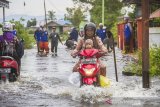 Warga melintasi banjir di Kabupaten Banjar, Kalimantan Selatan, Rabu (6/1/2021). Menurut Badan Penanggulangan Bencana Daerah (BPBD) Kabupaten Banjar, banjir setinggi lima hingga satu meter yang melanda pemukiman di sejumlah desa di Kabupaten Banjar tersebut dipicu oleh hujan dengan intensitas tinggi sehingga menyebabkan debit air sungai Martapura meluap. Foto Antaranews Kalsel/Bayu Pratama S.