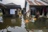 Sejumlah warga beraktivitas di depan rumah yang terendam banjir di Desa Sungai Rangas Ulu, Kabupaten Banjar, Kalimantan Selatan, Rabu (6/1/2021). Menurut Badan Penanggulangan Bencana Daerah (BPBD) Kabupaten Banjar, banjir setinggi lima hingga satu meter yang melanda pemukiman di sejumlah desa di Kabupaten Banjar tersebut dipicu oleh hujan dengan intensitas tinggi sehingga menyebabkan debit air sungai Martapura meluap.Foto Antaranews Kalsel/Bayu Pratama S.