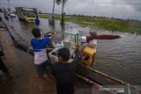 Sejumlah warga membantu pengendara melintasi titian kayu swadaya masyarakat untuk membantu pengendara roda dua di jalan Martapura Lama yang terendam banjir akibat luapan Sungai Martapura di Kabupaten Banjar, Kalimantan Selatan, Kamis (7/1/2021). Menurut warga setempat, banjir akibat luapan Sungai Martapura sudah berlangsung selama 15 hari merendam kawasan tersebut sehingga mengganggu aktivitas warga bahkan hingga saat ini pemerintah daerah belum ada memberikan bantuan apapun.Foto Antaranews Kalsel/Bayu Pratama S.