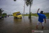 Seorang warga mengarahkan pengemudi truk saat melintas di jalan Martapura Lama yang terendam banjir akibat luapan Sungai Martapura di Kabupaten Banjar, Kalimantan Selatan, Kamis (7/1/2021). Menurut warga setempat, banjir akibat luapan Sungai Martapura sudah berlangsung selama 15 hari merendam kawasan tersebut sehingga mengganggu aktivitas warga, dan hingga Kamis (7/1/2021) pemerintah daerah belum memberikan bantuan apapun. Foto Antaranews Kalsel/Bayu Pratama S.