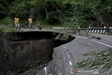 Petugas melintasi jembatan yang roboh di Talegong, Kabupaten Garut, Jawa Barat, Minggu (10/1/2021). Curah hujan yang tinggi di kawasan tersebut mengakibatkan jembatan Awisuti roboh hingga setengah badan jalan dan memutus akses penghubung antara Pangalengan, Talegong, Cisewu, dan Ranca Buaya bagi kendaraan roda empat. ANTARA JABAR/Candra Yanuarsyah/agr