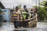 Warga menggunakan jasa gerobak angkut untuk melintas di Jalan Trans Kalimantan yang terendam banjir di Desa Banua Raya, Kecamatan Bati-Bati, Kabupaten Tanah Laut, Kalimantan Selatan, Senin (11/1/2021). Banjir yang melanda sejumlah kawasan di Kecamatan Bati Bati mengakibatkan jalan Trans Kalimantan yang menghubungkan Kota Banjarmasin-Kabupaten Tanah Bumbu dan Provinsi Kalimantan Timur tersebut lumpuh akibat terendam banjir. Foto Antaranews Kalsel/Bayu Pratama S.