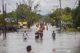 Warga melintas di Jalan Trans Kalimantan yang terendam Banjir di Desa Gunung Raja, Kecamatan Bati-Bati, Kabupaten Tanah Laut, Kalimantan Selatan, Senin (11/1/2021). Banjir yang melanda sejumlah kawasan di Kecamatan Bati Bati mengakibatkan jalan Trans Kalimantan yang menghubungkan Kota Banjarmasin-Kabupaten Tanah Bumbu dan Provinsi Kalimantan Timur tersebut lumpuh akibat terendam banjir. Foto Antaranews Kalsel/Bayu Pratama S.