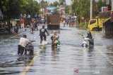 Sejumlah warga melintas di Jalan Trans Kalimantan yang terendam Banjir di Desa Banua Raya, Kecamatan Bati-Bati, Kabupaten Tanah Laut, Kalimantan Selatan, Senin (11/1/2021). Banjir yang melanda sejumlah kawasan di Kecamatan Bati Bati mengakibatkan jalan Trans Kalimantan yang menghubungkan Kota Banjarmasin-Kabupaten Tanah Bumbu dan Provinsi Kalimantan Timur tersebut lumpuh akibat terendam banjir. Foto Antaranews Kalsel/Bayu Pratama S.