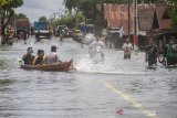 Sejumlah warga menggunakan perahu melintas di Jalan Trans Kalimantan yang terendam Banjir di Desa Banua Raya, Kecamatan Bati-Bati, Kabupaten Tanah Laut, Kalimantan Selatan, Senin (11/1/2021). Banjir yang melanda sejumlah kawasan di Kecamatan Bati Bati mengakibatkan jalan Trans Kalimantan yang menghubungkan Kota Banjarmasin-Kabupaten Tanah Bumbu dan Provinsi Kalimantan Timur tersebut lumpuh akibat terendam banjir. Foto Antaranews Kalsel/Bayu Pratama S.