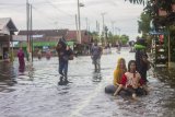 Sejumlah warga melintas di Jalan Trans Kalimantan yang terendam Banjir di Desa Banua Raya, Kecamatan Bati-Bati, Kabupaten Tanah Laut, Kalimantan Selatan, Senin (11/1/2021). Banjir yang melanda sejumlah kawasan di Kecamatan Bati Bati mengakibatkan jalan Trans Kalimantan yang menghubungkan Kota Banjarmasin-Kabupaten Tanah Bumbu dan Provinsi Kalimantan Timur tersebut lumpuh akibat terendam banjir. Foto Antaranews Kalsel/Bayu Pratama S.