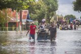 Warga menggunakan jasa gerobak angkut untuk melintas di Jalan Trans Kalimantan yang terendam banjir di Desa Banua Raya, Kecamatan Bati-Bati, Kabupaten Tanah Laut, Kalimantan Selatan, Senin (11/1/2021). Banjir yang melanda sejumlah kawasan di Kecamatan Bati Bati mengakibatkan jalan Trans Kalimantan yang menghubungkan Kota Banjarmasin-Kabupaten Tanah Bumbu dan Provinsi Kalimantan Timur tersebut lumpuh akibat terendam banjir. Foto Antaranews Kalsel/Bayu Pratama S.