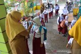 Guru mengecek suhu murid sebelum memasuki ruangan belajar di Sekolah Dasar Negeri 1 Banda Aceh, Aceh, Senin (11/1/2021). Dalam proses belajar mengajar secara tatap muka yang sudah berlangsung di daerah itu, pemerintah Aceh meminta seluruh Bupati dan Walikota melakukan sidak dan pengawasan ketat penerapan disiplin protokol kesehatan di sejumlah sekolah guna mencegah peningkatan kasus COVID-19. Antara Aceh/Ampelsa.