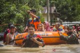 Relawan bersama TNI menggunakan perahu karet mengevakuasi warga yang terdampak banjir di Desa Sungai Raya, Kabupaten Banjar, Kalimantan Selatan, Selasa (12/1/2021). Ribuan rumah di enam desa Kecamatan Simpang Empat Kabupaten Banjar terendam banjir setinggi 50 cm hingga dua meter akibat intensitas curah hujan yang tinggi sehingga mengakibatkan Sungai Riam Kiwa meluap. Foto Antaranews Kalsel/Bayu Pratama S.