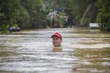 Warga melintasi banjir di Desa Sungai Raya, Kabupaten Banjar, Kalimantan Selatan, Selasa (12/1/2021). Ribuan rumah di enam desa Kecamatan Simpang Empat Kabupaten Banjar terendam banjir setinggi 50 cm hingga dua meter akibat intensitas curah hujan yang tinggi sehingga mengakibatkan Sungai Riam Kiwa meluap. Foto Antaranews Kalsel/Bayu Pratama S.