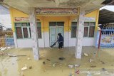 Seorang guru membersihkan sampah di sekitar ruang perpustakaan SDN Eretan Wetan 1 yang terendam banjir rob di Kandanghaur, Indramayu, Jawa Barat, Rabu (13/1/2021). Banjir rob akibat pasang air laut itu merendam ratusan rumah warga, bangunan sekolah dan mushola di kecamatan itu. ANTARA JABAR/Dedhez Anggara/agr