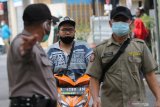 Petugas menghentikan warga yang tidak mengenakan masker di dekat kelurahan Ploso, Surabaya, Jawa Timur, Selasa (12/1/2021). Operasi protokol kesehatan itu menjaring sedikitnya 20 pelanggar yang tidak mengenakan masker dengan benar dan tidak mengenakan masker sama sekali dan para pelanggar dikenakan sanksi denda. Antara Jatim/Didik/Zk