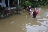 Warga melintasi banjir untuk mengungsi di Balai Desa Wonoasri, Tempurejo, Jember, Jawa Timur, Jumat (15/1/2021). Sebanyak 2.558 KK di wilayah tersebut terdampak banjir dengan ketinggian air  hingga dua meter. Antara Jatim/Seno/ZK