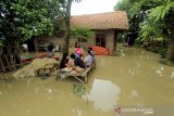 Warga berada di sekitar rumahnya yang terendam banjir di desa Kenanga, Indramayu, Jawa Barat, Jumat (15/1/2021). Banjir akibat luapan sungai Cimanuk tersebut merendam puluhan rumah di desa tersebut. ANTARA JABAR/Dedhez Anggara/agr