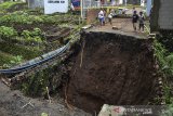 Sejumlah warga melihat kondisi jembatan yang amblas di Sindangrasa, Kabupaten Ciamis, Jawa Barat, Jumat (15/1/2021). Curah hujan yang tinggi mengakibatkan jembatan atau jalan alternatif penghubung antar kecamatan amblas dan terputus. ANTARA JABAR/Adeng Bustomi/agr