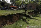 Warga mengamati lokasi tanah yang amblas akibat bencana tanah bergerak di Desa Lamkleng Kecamatan Cot Glie, Aceh Besar, Aceh, Sabtu (16/1/2021). Bencana yang menyebabkan amblasnya tanah sepanjang ratusan meter dengan kedalaman lebih dari satu meter di pinggiran Krueng (sungai) Aceh itu mengancam 15 unit rumah warga. Antara Aceh/Irwansyah Putra.