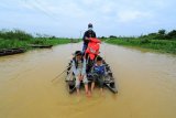 Warga menggunakan jasa perahu penyeberangan melintasi Jalan Lintas Jambi-Berbak yang terendam banjir luapan Sungai Batanghari di Desa Gedong Karya, Muarojambi, Jambi, Jumat (15/1/2021). Banjir di jalan provinsi yang terus meninggi sejak awal Januari tersebut memutus akses pengendara sepeda motor sehingga dimanfaatkan warga sekitar dengan menyediakan jasa perahu penyeberangan dengan tarif Rp15 ribu per motor. ANTARA FOTO/Wahdi Septiawan/foc.