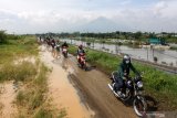 Sejumlah pengendara sepeda motor melewati tanggul penahan lumpur Lapindo untuk menghindari banjir di jalan Raya Porong, Sidoarjo, Jawa Timur, Senin (18/1/2021). Curah hujan yang tinggi sejak Minggu (17/1) malam mengakibatkan banjir yang merendam Jalan Raya Porong sehingga mengganggu kelancaran transportasi umum. Antara Jatim/Umarul Faruq/zk.