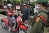 Pecalang dan petugas Linmas menegur pengendara sepeda motor yang tidak menerapkan protokol kesehatan dalam Pemberlakuan Pembatasan Kegiatan Masyarakat (PPKM) tingkat desa/kelurahan di Denpasar, Bali, Senin (18/1/2021). PPKM tingkat desa/kelurahan di Denpasar tersebut digelar pada 18 Januari hingga 18 Februari 2021 menyusul meningkatnya kasus positif COVID-19 di wilayah itu. ANTARA FOTO/Nyoman Hendra Wibowo/nym