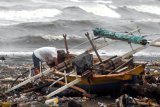 Seorang nelayan memeriksa perahunya yang rusak terhempas ombak di pesisir pantai di Manado, Sulawesi Utara, Senin (18/1/2021). Ombak setinggi empat meter yang menerjang pesisir pantai Manado membawa tumpukan sampah serta merusak sejumlah lapak dan bangunan semi permanen milik warga. ANTARA FOTO/Adwit B Pramono/nym.