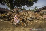 Warga menggunakan sepeda melintas di dekat puing-puing rumah akibat banjir bandang di Desa Waki, Kecamatan Batu Benawa,Kabupaten Hulu Sungai Tengah, Kalimantan Selatan,Kamis (21/1/2021). Berdasarkan data bencana alam banjir Badan Penanggulangan Bencana Daerah (BPBD) Kabupaten Hulu Sungai Tengah pada Selasa (18/1/2021) sebanyak 57.624 jiwa terdampak banjir serta sembilan jiwa dinyatakan meninggal dunia dan enam jiwa hilang. Foto Antaranews Kalsel/Bayu Pratama S.