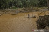 Sejumlah warga menyeberang sungai menggunakan tali akibat jembatan rusak diterjang banjir bandang di Desa Waki, Kabupaten Hulu Sungai Tengah, Kalimantan Selatan, Rabu (21/1/2021). Berdasarkan data Badan Penanggulangan Bencana Daerah (BPBD) Provinsi Kalsel pada Rabu (20/1/2021) sebanyak 21 Jembatan, 110 tempat ibadah, 76 sekolah serta 18.294 meter jalan terdampak banjir dan longsor di Kalimantan Selatan. Foto Antaranews Kalsel/Bayu Pratama S.