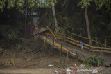 Seorang anak bermain di jembatan rusak akibat banjir bandang di Desa Waki, Kabupaten Hulu Sungai Tengah, Kalimantan Selatan, Kamis (21/1/2021). Berdasarkan data Badan Penanggulangan Bencana Daerah (BPBD) Provinsi Kalsel pada Rabu (20/1/2021) sebanyak 21 Jembatan, 110 tempat ibadah, 76 sekolah serta 18.294 meter jalan terdampak banjir dan longsor di Kalimantan Selatan. Foto Antaranews Kalsel/Bayu Pratama S.