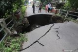 Warga mengamati jembatan rusak di Desa Gedangsewu, Kediri, Jawa Timur, Sabtu (23/1/2021). Jembatang yang menjadi akses utama antar kecamatan di wilayah tersebut ambrol karena tergerus derasnya aliran sungai Bening usai hujan deras. Antara Jatim/Prasetia Fauzani/zk.