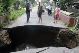 Warga mengamati jembatan rusak di Desa Gedangsewu, Kediri, Jawa Timur, Sabtu (23/1/2021). Jembatang yang menjadi akses utama antar kecamatan di wilayah tersebut ambrol karena tergerus derasnya aliran sungai Bening usai hujan deras. Antara Jatim/Prasetia Fauzani/zk.