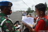 Petugas memeriksa identitas pengendara saat penyekatan wilayah dalam rangka Pelaksanaan Pembatasan Kegiatan Masyarakat (PPKM) di Kota Madiun, Jawa Timur, Kamis (21/1/2021). Petugas gabugan terdiri Polri, TNI, Dinas Perhubungan, Satpol PP, Dinas Kesehatan melakukan penyekatan di sejumlah lokasi jalan masuk Kota Madiun dengan sasaran pengendara dari luar kota yang tidak bisa menunjukkan surat keterangan bebas COVID-19 serta pelanggar protokol kesehatan, dan pada hari pertama pelaksanaan Kamis (21/1) dari 276 kendaraan bermotor yang diperiksa sebanyak 77 kendaraan tidak diperbolehkan masuk Kota Madiun dan harus putar balik, 44 pelanggar protokol kesehatan mendapatkan teguran tertulis guna pencegahan penularan COVID-19. Antara Jatim/Siswowidodo/zk.