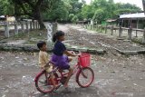 Dua orang anak bermain sepeda di tempat penambatan sapi di pasar hewan yang ditutup di Ngawi, Jawa Timur, Rabu (27/1/2021). Pemerintah setempat menutup sepuluh pasar hewan di kawasan tersebut guna mencegah makin meluasnya penyebaran COVID-19. Antara Jatim/Ari Bowo Sucipto/zk.