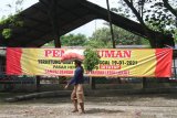 Seorang pencari rumput melintas di depan spanduk penutupan pasar hewan di Ngawi, Jawa Timur, Rabu (27/1/2021). Pemerintah setempat menutup sepuluh pasar hewan di kawasan tersebut guna mencegah makin meluasnya penyebaran COVID-19. Antara Jatim/Ari Bowo Sucipto/zk.