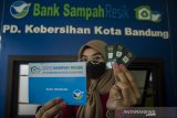 Petugas menunjukkan buku tabungan nasabah dan emas mini untuk program Nabung Sampah Jadi Emas di Bank Sampah Resik, Bandung, Jawa Barat, Kamis (28/1/2021). Pemerintah Kota Bandung membuat program tersebut guna mengajak warga menabung sampah anorganik yang telah dipilah seperti botol, kaleng, plastik dan kardus yang nantinya akan ditukarkan dengan emas mini mulai dari 0.025 gram hingga1 gram. ANTARA JABAR/Novrian Arbi/agr