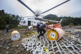 Petugas menurunkan logistik bantuan bahan bakar minyak (BBM) di Desa Datar Ajab, Kabupaten Hulu Sungai Tengah, Kalimantan Selatan, Jumat (29/1/2021). TNI Angkatan Udara Lanud Sjamsudin Noor menggunakan helikopter milik Badan Nasional Penanggulangan Bencana (BNPB) mendistribusikan BBM jenis pertamax dan minyak tanah bantuan dari PT Pertamina (Persero) ke lokasi pengungsian di wilayah pedalaman Pegunungan Meratus untuk digunakan sebagai operasional para relawan serta kebutuhan dapur umum. Foto Antaranews Kalsel/Bayu Pratama S.