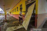 Warga melihat kondisi sebuah bangunan sekolah dasar negeri yang terdampak banjir bandang di Desa Datar Ajab, Kabupaten Hulu Sungai Tengah, Kalimantan Selatan, Jumat (29/1/2021). Berdasarkan data terbaru dari Badan Penanggulangan Bencana Daerah (BPBD) Provinsi Kalimantan Selatan pada Kamis (28/1/2021), bencana alam banjir di 11 Kabupaten/Kota di Kalimantan Selatan mengakibatan sebanyak 135.656 warga mengungsi serta fasilitas dan insfrastruktur sebanyak 1.419 sekolah, 838 tempat ibadah, 128 jembatan, 101.903 rumah terendam dan 48.714 Hektare lahan sawah terdampak banjir. Foto Antaranews Kalsel/Bayu Pratama S.