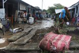 Warga melewati endapan lumpur pascabanjir di salah satu perumahan Kelurahan Tegal Besar, Kaliwates, Jember, Jawa Timur, Sabtu (30/1/2021). Data Badan Penanggulangan Bencana Daerah (BPBD) Jember, menyebutkan sebanyak 442 rumah warga di daerah aliran sungai (DAS) Bedadung di 13 desa/kelurahan di 7 kecamatan terkena dampak banjir hingga ketinggian lebih dari satu meter. Antara Jatim/Seno/ZK