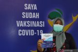 Seorang tenaga kesehatan memperlihatkan kartu vaksinasi COVID-19 usai mengikuti vaksinasi tahap pertama di Puskesmas Mejayan, Kabupaten Madiun, Jawa Timur, Jumat (29/1/2021). Kabupaten Madiun menerima sebanyak 2.340 dosis vaksin COVID-19 tahap pertama untuk tenaga kesehatan guna pencegahan penularan COVID-19. Antara Jatim/Siswowidodo/zk