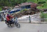 Warga melintasi jembatan pasca banjir yang memutus akses jalan antar kabupaten di Desa Kalianyar, Ijen, Bondowoso, Jawa Timur, Selasa (2/2/2021). Personel gabungan TNI, POLRI, BPBD, Perhutani membersihkan material longsor berupa pohon, batu, tanah akibat banjir dan longsor menutup akses menuju kawasan Taman Wisata Alam Kawah IjenÂ dan akses menuju Kabupaten Banyuwangi. Antara Jatim/Seno/zk.