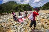 Warga memikul paket sembako bantuan presiden di pedalaman Pegunungan Meratus, Desa Datar Ajab, Kabupaten Hulu Sungai Tengah, Kalimantan Selatan, Selasa (2/2/2021). Presiden Joko Widodo melalui Badan Nasional Penanggulangan Bencana (BNPB) menyalurkan 20 ribu paket sembako untuk memenuhi kebutuhan korban banjir di 11 Kabupaten/Kota Provinsi Kalimantan Selatan. Foto Antaranews Kalsel/Bayu Pratama S.