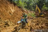 Warga menggunakan sepeda motor melintasi jalan bekas tanah longsor di Desa Datar Ajab, Kabupaten Hulu Sungai Tengah, Kalimantan Selatan, Kamis (4/2/2021). Hujan lebat pada Rabu (13/1) lalu, mengakibatkan terjadi tanah longsor dan banjir bandang yang menutupi akses jalan desa dan lahan pertanian serta merenggut 10 korban jiwa. Foto Antaranews Kalsel/Bayu Pratama S.