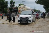 Sejumlah warga secara sukarela mengatur lalu lintas di jalan nasional Surabaya-Madiun yang tergenang banjir di Bandar Kedungmulyo Kabupaten Jombang, Jawa Timur, Kamis (4/2/2021). Banjir yang disebabkan meluapnya sungai avur Brawijaya di desa setempat mengakibatkan kemacetan kendaraan mengular hingga 1 kilometer, selain itu juga menggenangi puluhan rumah serta warung makan. Antara Jatim/Syaiful Arif/zk.