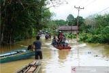 Sejumlah warga menggunakan perahu saat melintasi ruas jalan utama menuju Pos Lintas Batas Negara (PLBN) Jagoi Babang yang terendam banjir di Kabupaten Bengkayang, Kalimantan Barat, Jumat (5/2/2021). Banjir setinggi 2-4 meter yang melanda delapan desa di Kecamatan Ledo dan dua desa di Kecamatan Sanggau Ledo, Kabupaten Bengkayang yang berbatasan dengan Malaysia tersebut terjadi sejak Rabu (3/2/2021), serta mengakibatkan akses menuju perbatasan terputus. ANTARA FOTO/HO/Andas/jhw/aww.