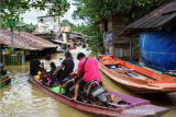 Sejumlah warga menaiki perahu melintasi banjir yang merendam permukiman di Desa Lesabela, Kecamatan Ledo, Kabupaten Bengkayang, Kalimantan Barat, Jumat (5/2/2021). Banjir setinggi 2-4 meter yang melanda delapan desa di Kecamatan Ledo dan dua desa di Kecamatan Sanggau Ledo, Kabupaten Bengkayang yang berbatasan dengan Malaysia tersebut terjadi sejak Rabu (3/2/2021), serta mengakibatkan akses menuju perbatasan terputus. ANTARA FOTO/HO/Andas/jhw/aww.